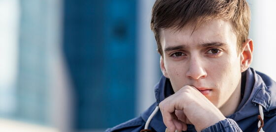 Un jeune homme regarde pensivement.