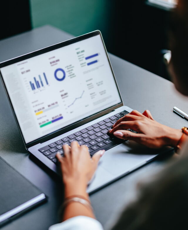 Eine Person liest am Laptop Finanzdaten.
